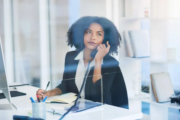 På vakt med noen viktige klienter. Skutt av en ung forretningskvinne som snakket i en telefon på et kontor. – stockfoto