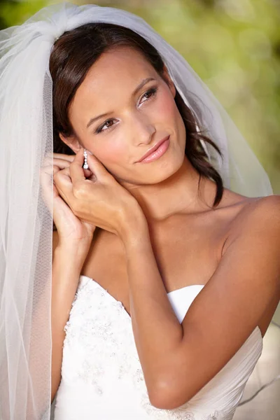 Réglages de dernière minute. Belle mariée ajustant ses boucles d'oreilles le jour de son mariage. — Photo