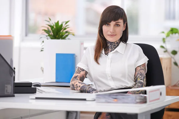 Exercício de auto-expressão. Uma foto de uma empresária tatuada sentada em sua mesa em seu escritório. — Fotografia de Stock