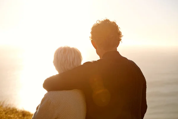 Deler et øyeblikks refleksjon. Korrupt syn på et eldre par som står på en åsside sammen. – stockfoto