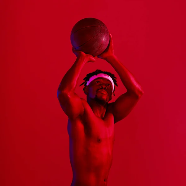 Стреляй. Красный отфильтрованный снимок молодого спортсмена, позирующего с баскетболом в студии. — стоковое фото