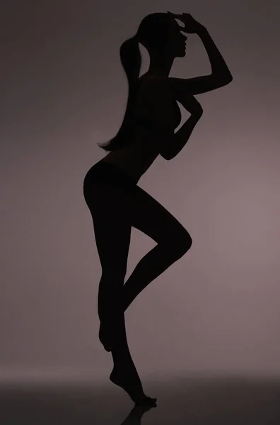 Beleza silhueta. silhueta de estúdio de uma mulher bonita em lingerie contra um fundo cinza. — Fotografia de Stock