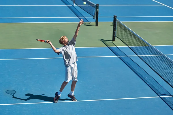 Op een dag zal het een begin zijn. Opname van een jonge jongen die tennis speelt op een zonnige dag. — Stockfoto