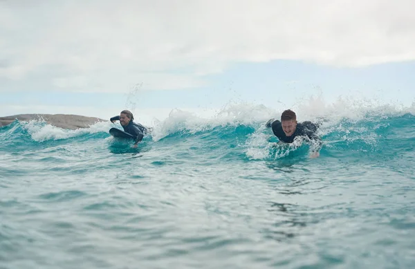 Surfen stelt ons in staat om één te zijn met de natuur. Een foto van een jong stel dat samen op het strand surft.. — Stockfoto