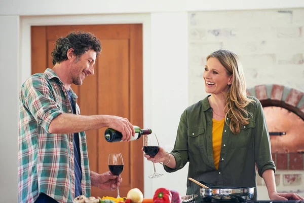 Milyen volt a napod, drágám? Egy boldog érett párról, akik bort iszogatnak, miközben együtt főznek otthon.. — Stock Fotó