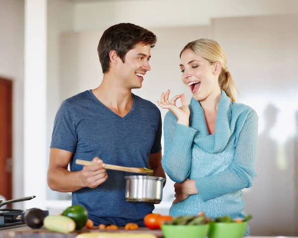 Perfecto. Shot of a handsome young man giving his wife a taste of his cooking. — Stock Photo, Image