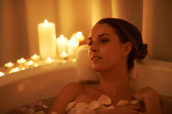Calmado por el ambiente y un baño caliente. Recortado disparo de una hermosa mujer relajándose en un baño iluminado con velas. — Foto de Stock