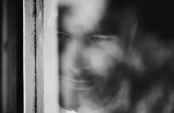 Blurred viewpoint. Closeup of a thoughtful young man seen through a window. — Stock Photo, Image