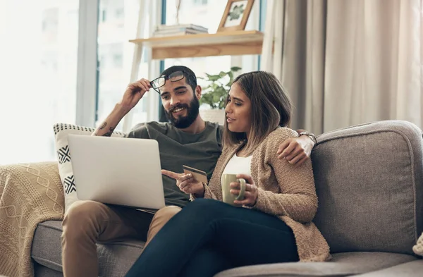 Zadowolony klient to wygodny klient. Zdjęcie młodej pary używającej laptopa i karty kredytowej na kanapie w domu. — Zdjęcie stockowe