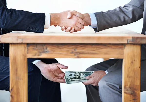 Unter-dem-Tisch-Transaktionen.... Schnappschuss von zwei Geschäftsleuten, die sich die Hände schütteln, während Geld unter einem Tisch die Hände reicht. — Stockfoto