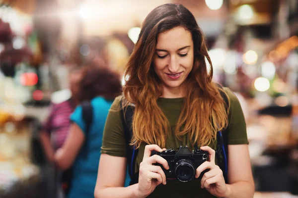 Turistlerin en iyi yaptığı şeyi yapma zamanı. Gün içinde elinde kamera olan neşeli bir genç kadının marketin önünde dikilirken ekrana bakması.. — Stok fotoğraf