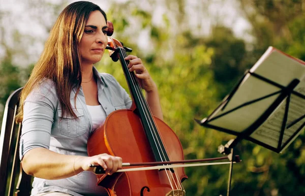 Prende ogni nota sul serio. Colpo ritagliato di una bella donna che suona un violoncello nel cortile. — Foto Stock