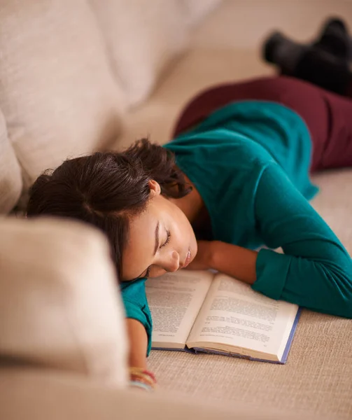 我们总是喜欢听睡前故事。一个拿着一本书在沙发上打盹的年轻女子的剪影. — 图库照片