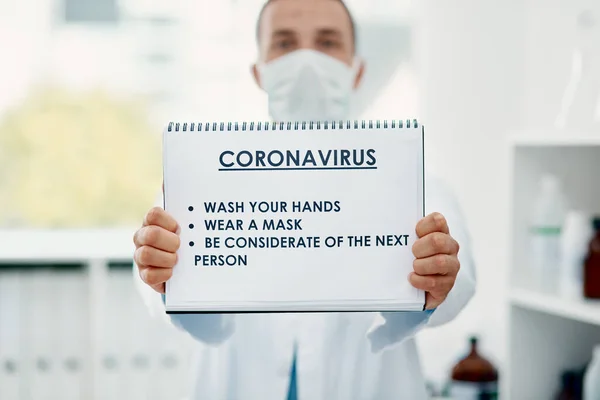 Tun Sie Ihren Teil, um dem Virus auszuweichen. Aufnahme eines Wissenschaftlers mit einem Schild mit einer Liste von COVID-19-Präventionsmaßnahmen in einem Labor. — Stockfoto