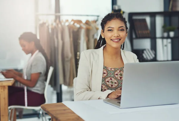Inspiratie krijgen van haar concurrenten online. Foto van een mode-ontwerper werkt op haar laptop met haar collega wazig uit. — Stockfoto