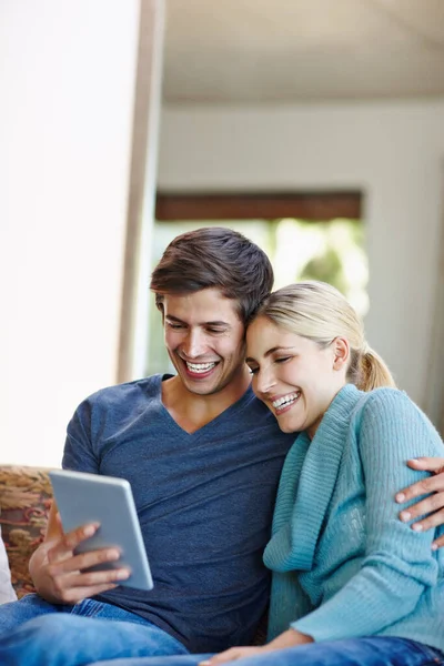 Viendo algo loco en la web. Foto de una feliz pareja joven usando una tableta digital juntos en el sofá en casa. —  Fotos de Stock