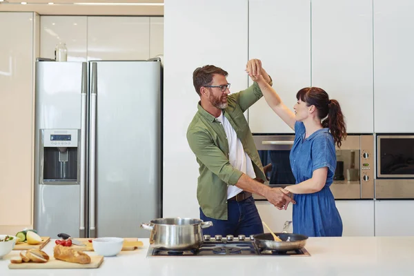 Sharing another fun moment together. Shot of a mature couple dancing while cooking together at home. — Stock Photo, Image