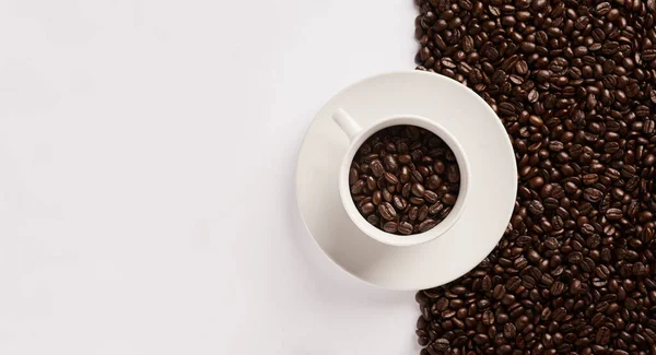 Para hacerme feliz, hazme café. Primer plano de una taza llena de granos de café sobre un fondo medio y medio. — Foto de Stock
