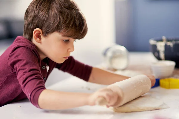 Vai avanti e basta. Girato di un ragazzino stendere la pasta in cucina. — Foto Stock