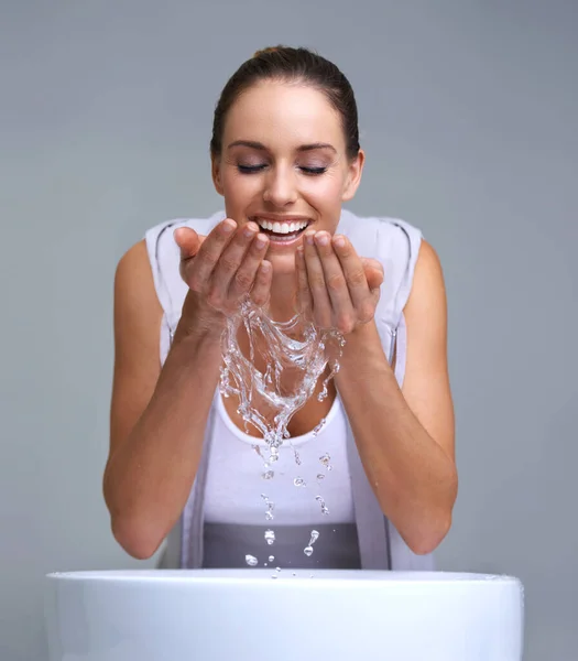 Que refrescante. Uma jovem atraente lavando o rosto. — Fotografia de Stock