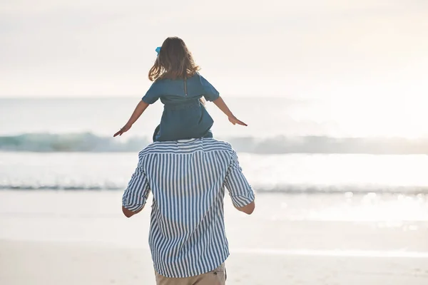 Tatínkova holčička. Zpětný záběr nerozpoznatelného otce nesoucího svou dceru na ramenou během příjemného dne na pláži. — Stock fotografie