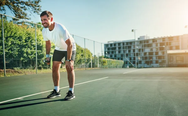 A natureza de corrida, parada e pivotante do tênis pode causar lesões. Tiro de um jovem desportivo segurando o joelho com dor enquanto jogava tênis em uma quadra de tênis. — Fotografia de Stock