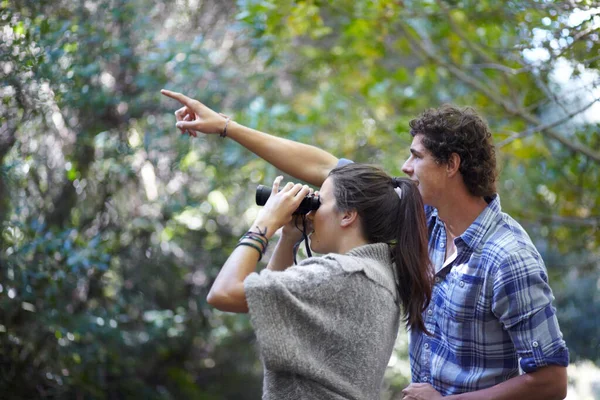 学习自然。一个年轻人用双筒望远镜向他的女朋友指点什么. — 图库照片