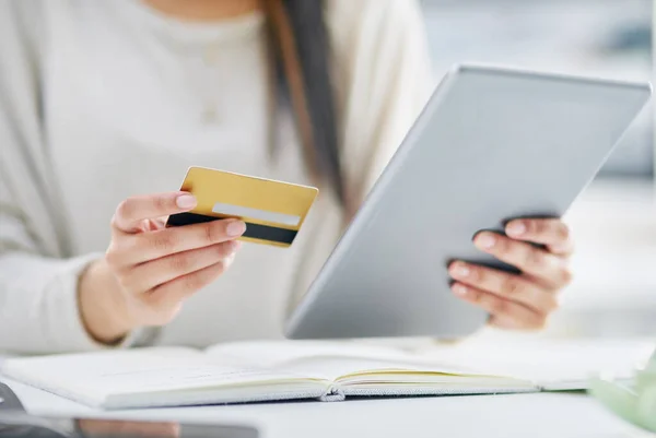 Fazendo alguns furtos rápidos online. Foto de perto de uma empresária irreconhecível usando um tablet digital e um cartão de crédito em um escritório. — Fotografia de Stock