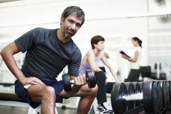 Todos deberían ir al gimnasio de vez en cuando. Retrato recortado de un joven guapo haciendo ejercicio con pesas en el gimnasio. —  Fotos de Stock