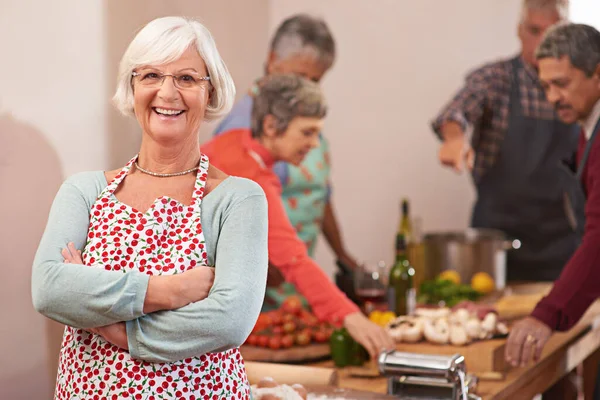 Me encanta hacer cenas. Retrato de una mujer mayor con amigos cocinando juntos en el fondo. — Foto de Stock