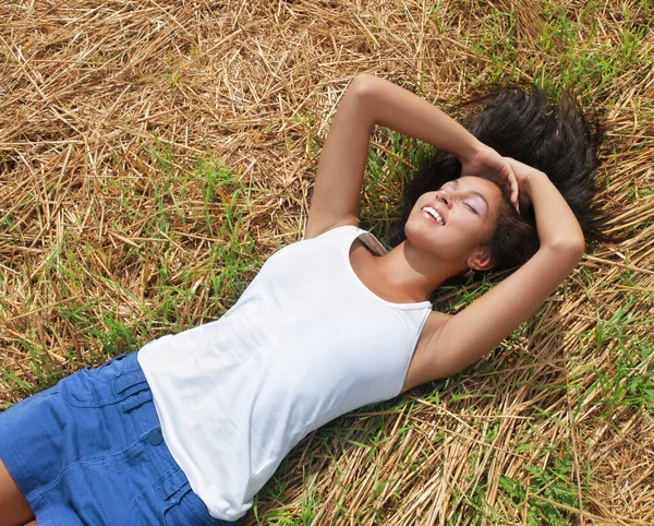 Jediné, co potřebuju, jsem já. Snímek krásné mladé ženy odpočívající na posteli trávy venku. — Stock fotografie