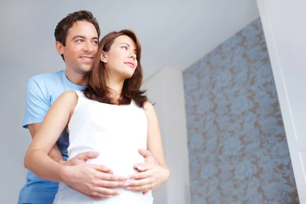 Aspirasi untuk bayi mereka. Anak muda memegang perut pacarnya yang sedang hamil saat mereka melihat dalam pikiran. — Stok Foto