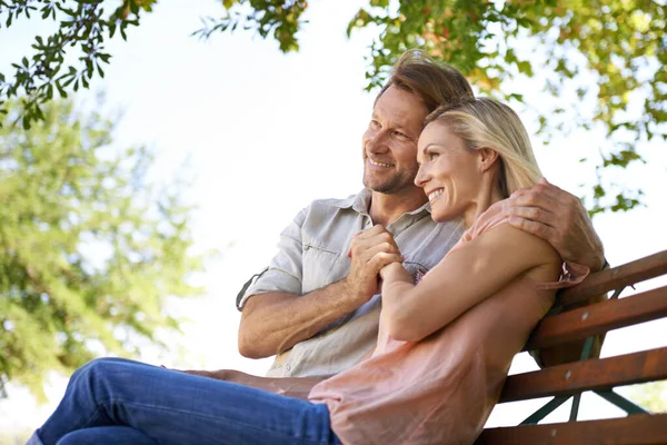 愛は自然のシンプルさに触発されています。公園のベンチに座って幸せな成熟したカップルのショット. — ストック写真
