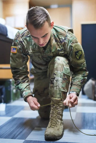 勇敢なのは戦闘ブーツを履いた男だ。士官学校の寮でブーツの靴ひもを結ぶ若い兵士のショット. — ストック写真