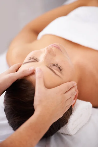 Recuando para um lugar de relaxamento tranquilo. Uma jovem deitada em um spa de beleza recebendo uma massagem relaxante na cabeça. — Fotografia de Stock