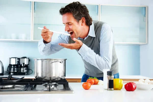 Homem maduro provando comida que ele está cozinhando. Retrato de um homem maduro degustando a comida que está cozinhando. — Fotografia de Stock