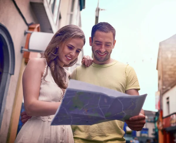 Viaggiare è un'esperienza condivisa al meglio. Girato di una giovane coppia felice che legge una mappa mentre esplora una città straniera insieme. — Foto Stock