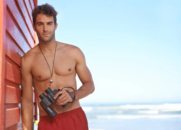 Está buscando peligro en el agua. Un joven salvavidas guapo en la playa. —  Fotos de Stock