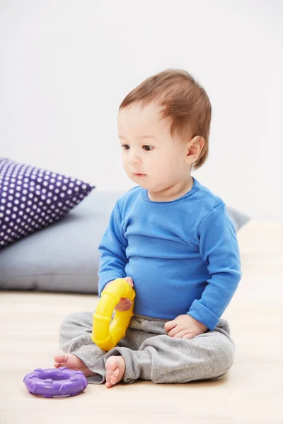 Es un pequeñín juguetón... Shot de un lindo bebé sentado en el suelo y jugando con sus juguetes. —  Fotos de Stock