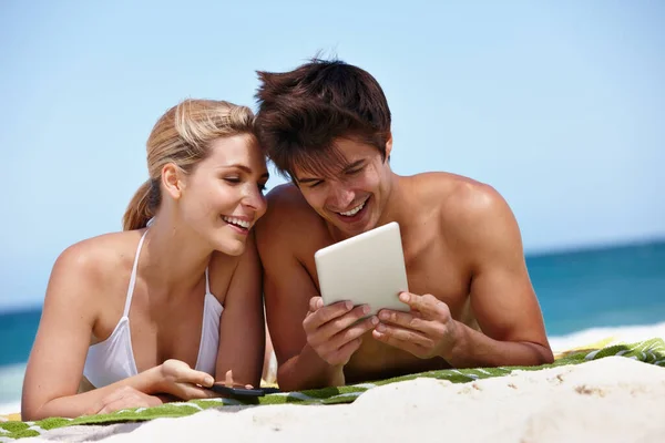 夏のサーフィン。ビーチでタブレットで何かを見て幸せな若いカップルのショット. — ストック写真