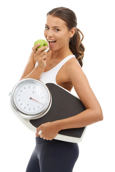 Sabroso y saludable. Una joven en forma llevando una balanza y disfrutando de una deliciosa manzana. — Foto de Stock