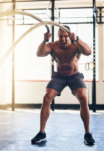 Der Aufbau einiger toller Ergebnisse. Aufnahme eines muskulösen jungen Mannes, der in der Turnhalle mit schweren Seilen trainiert. — Stockfoto