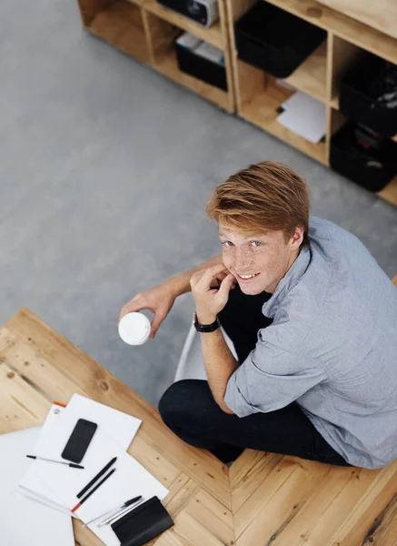 Disfrutando de una taza de café en la oficina. Retrato de un joven diseñador sosteniendo una taza de café mientras está sentado en la oficina. — Foto de Stock