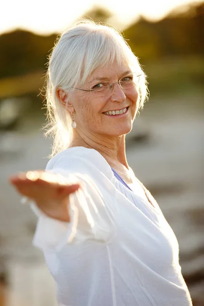 Zawsze czuję się lepiej po treningu jogi. Portret atrakcyjnej dojrzałej kobiety uprawiającej jogę na plaży o zachodzie słońca. — Zdjęcie stockowe