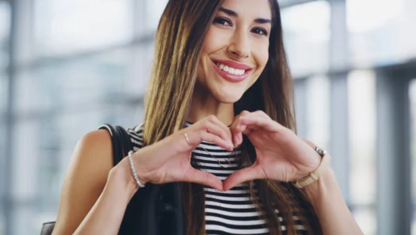 He invertido mi corazón en tener éxito. Recorte de una joven mujer de negocios mostrando un signo de corazón mientras camina a través de una oficina moderna. —  Fotos de Stock