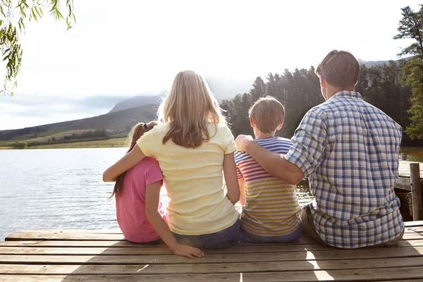 自然の美しさとの結合。田舎の湖の上の桟橋に座っている家族の後部ビューショット. — ストック写真