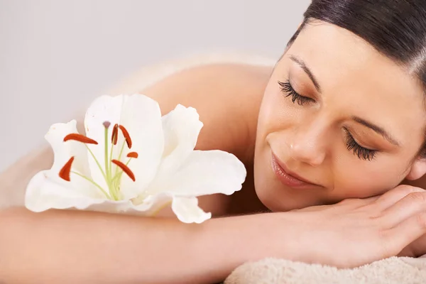 Natural beauty starts with taking time out. Cropped view of a young woman relaxing at a spa with a fresh flower nearby. — Stock Photo, Image