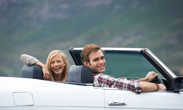 On the road to adventure. A young couple driving in a convertible on a road trip. — Stock Photo, Image