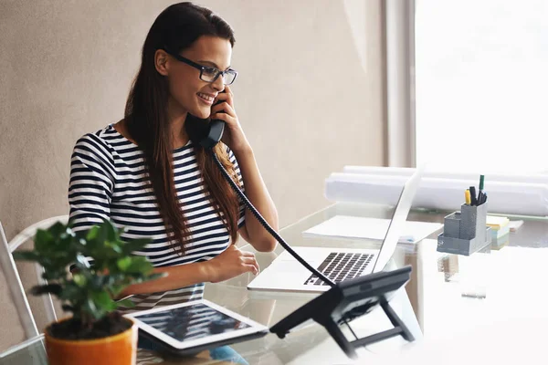 Die Empfangsdame... und alles andere. Aufnahme einer jungen Geschäftsfrau, die mit ihrem Laptop telefoniert. — Stockfoto