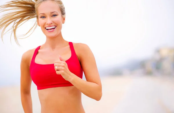 Correre è uno stile di vita. Girato di una giovane donna che fa jogging vicino alla spiaggia. — Foto Stock